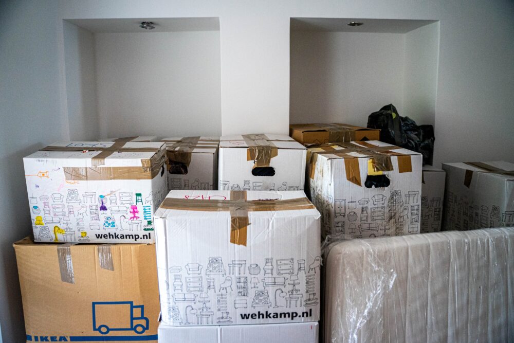 Moving boxes and a mover outside a Japanese apartment, illustrating a within-Japan move timeline