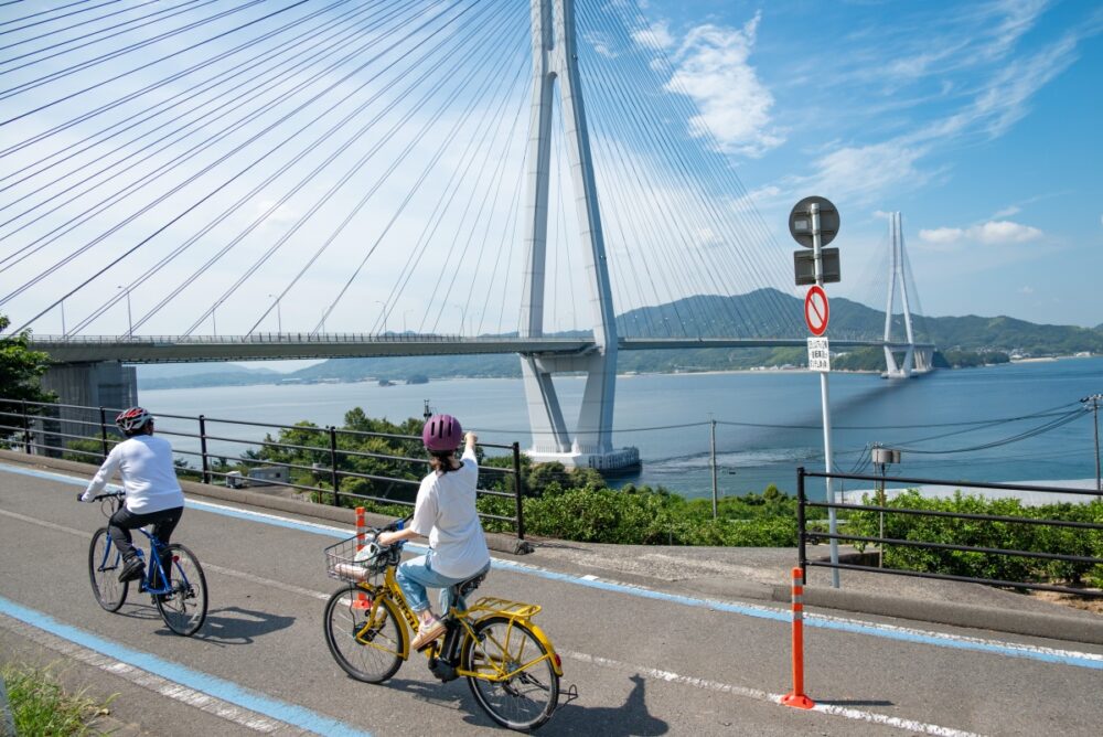 Cyclist riding the Shimanami Kaido cycling route pointing a sea bridge in Japan