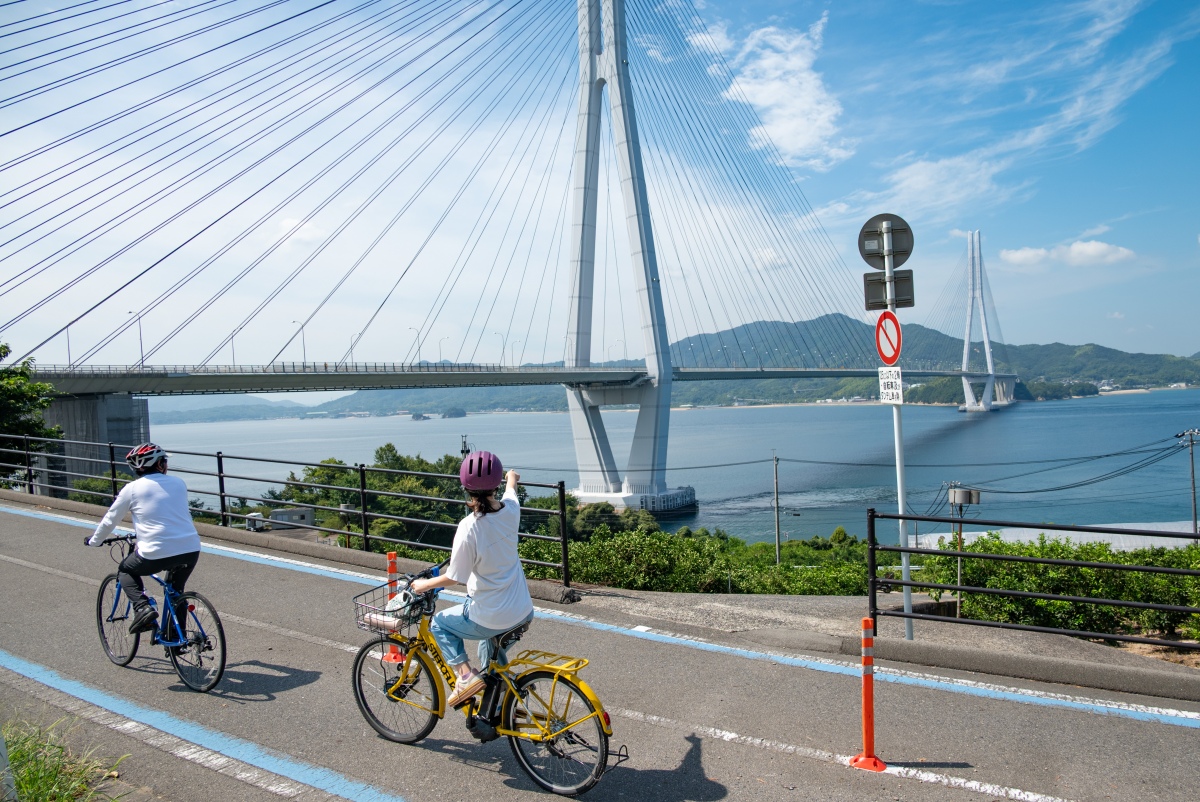 Cyclist riding the Shimanami Kaido cycling route pointing a sea bridge in Japan