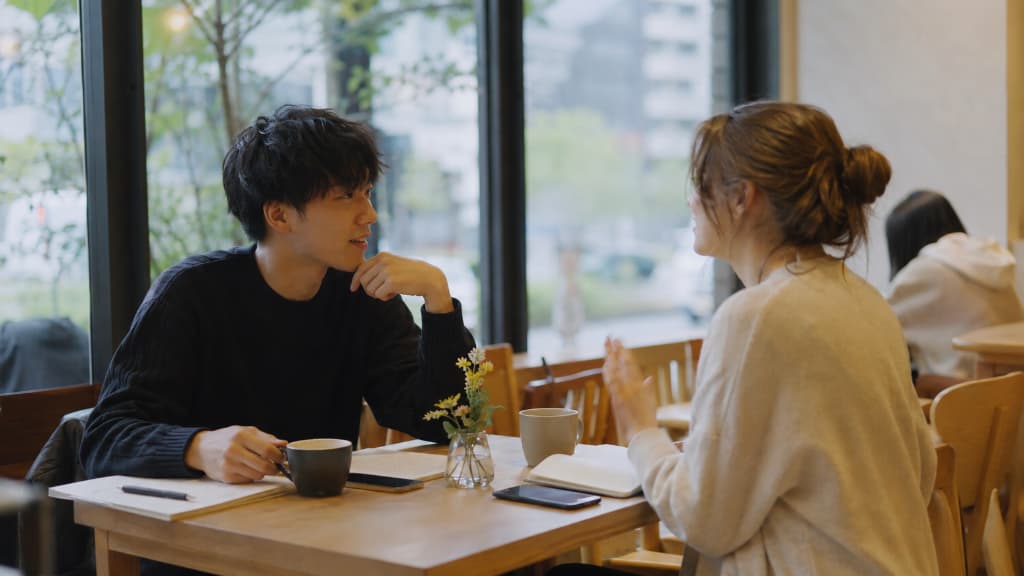 Two people chatting at a language exchange in a Tokyo cafe