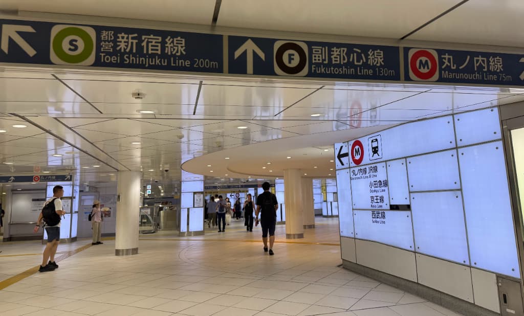 Color-coded subway signs with station number codes in a Tokyo metro station